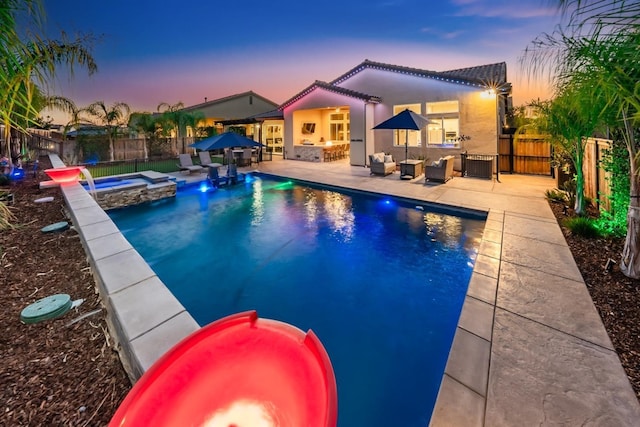 pool at dusk featuring a patio area, a fenced backyard, a pool with connected hot tub, and an outdoor hangout area