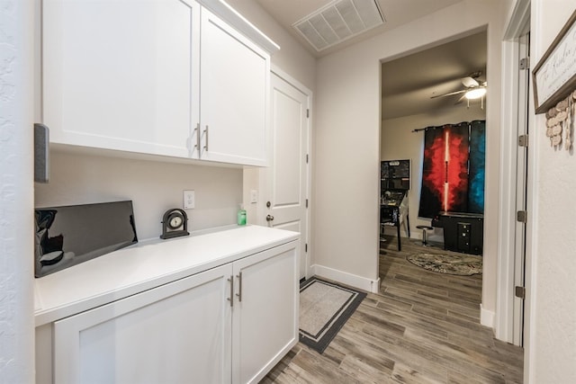 laundry area featuring ceiling fan, light wood finished floors, visible vents, and baseboards