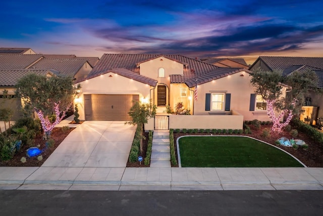 mediterranean / spanish-style house with a garage, concrete driveway, a tiled roof, and stucco siding