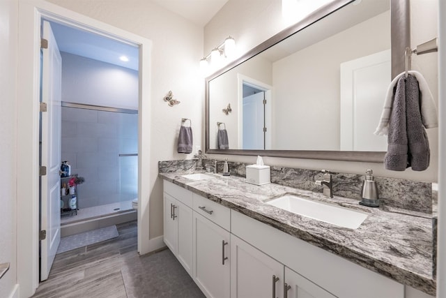 full bath featuring double vanity, a shower stall, toilet, and a sink