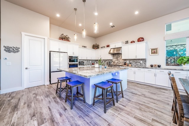 kitchen featuring double oven, freestanding refrigerator, backsplash, and under cabinet range hood