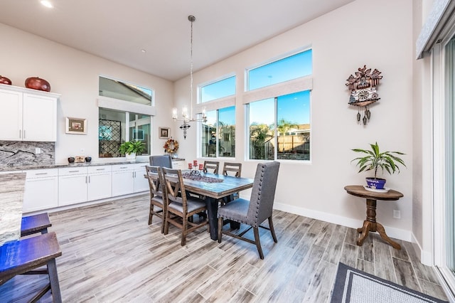 dining room with a chandelier, light wood-style flooring, and baseboards