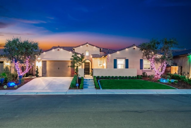 mediterranean / spanish home featuring stucco siding, a front yard, a garage, driveway, and a tiled roof