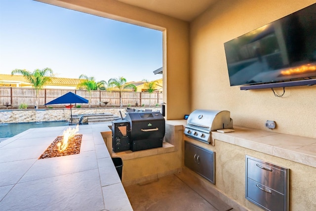 view of patio featuring a fenced in pool, grilling area, exterior kitchen, a fenced backyard, and a fire pit