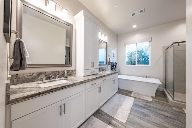 bathroom with double vanity, visible vents, a freestanding bath, a stall shower, and a sink