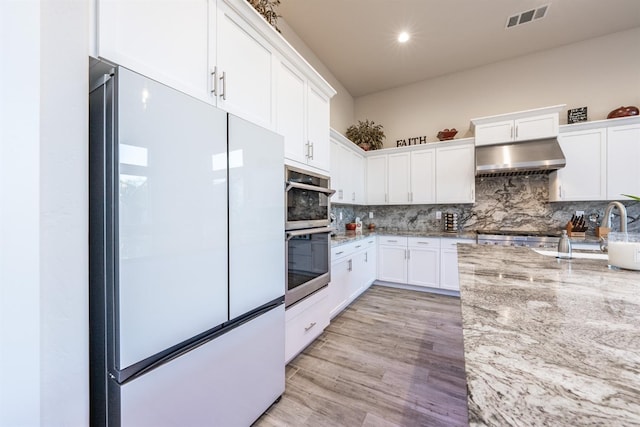 kitchen featuring visible vents, white cabinets, appliances with stainless steel finishes, light stone countertops, and under cabinet range hood