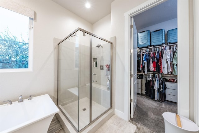 bathroom featuring a stall shower, a walk in closet, and a soaking tub