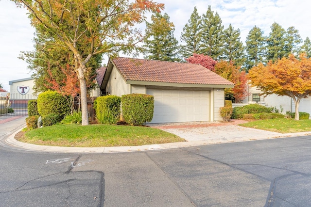 view of front of property with stucco siding, fence, a tile roof, and a garage