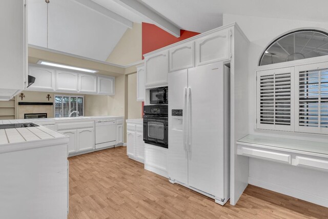 kitchen with black appliances, beamed ceiling, light hardwood / wood-style floors, white cabinetry, and tile counters