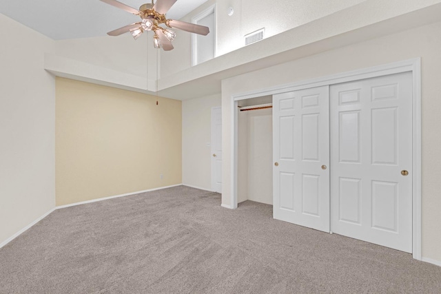 unfurnished bedroom featuring a closet, ceiling fan, a towering ceiling, and carpet floors