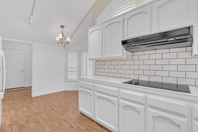 kitchen with black electric stovetop, white cabinets, light wood-type flooring, and an inviting chandelier