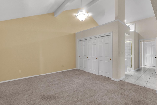 unfurnished bedroom featuring a closet, beamed ceiling, light colored carpet, and high vaulted ceiling