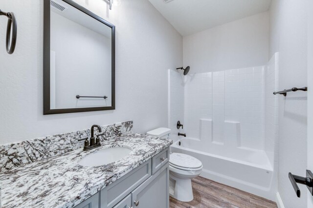 full bathroom featuring wood-type flooring, vanity,  shower combination, and toilet