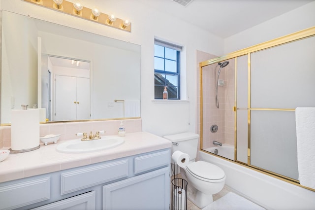 full bathroom with enclosed tub / shower combo, vanity, and toilet