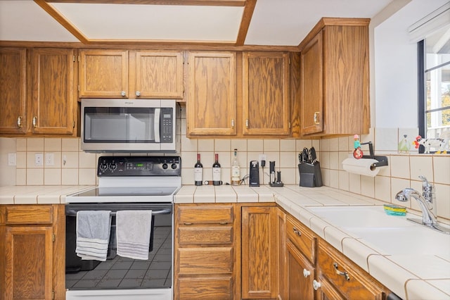 kitchen featuring range with electric stovetop, tasteful backsplash, sink, and tile countertops