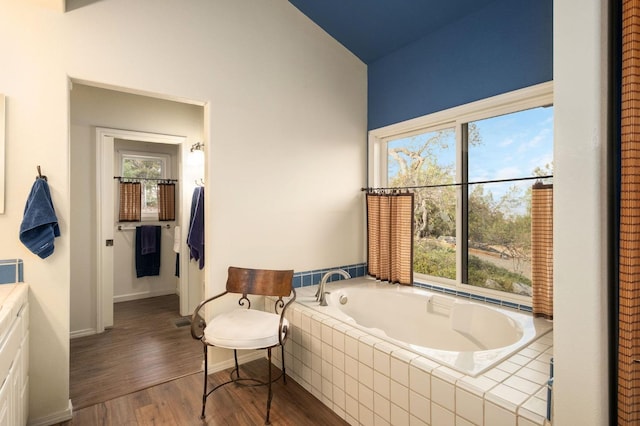 bathroom featuring wood-type flooring, tiled bath, and lofted ceiling