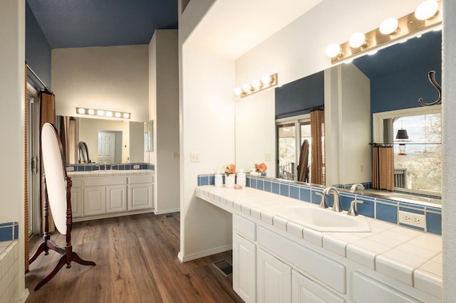 bathroom featuring hardwood / wood-style floors, vanity, and vaulted ceiling