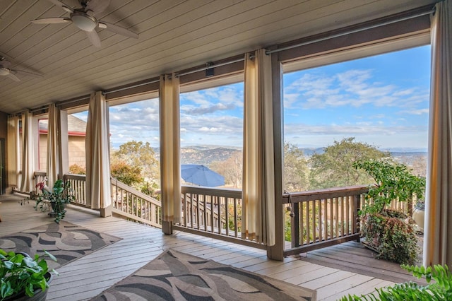 unfurnished sunroom with a mountain view and ceiling fan