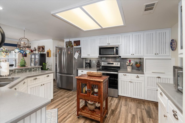 kitchen with white cabinets, wood-type flooring, and appliances with stainless steel finishes