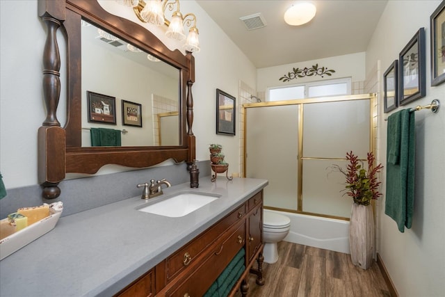 full bathroom featuring hardwood / wood-style floors, vanity, bath / shower combo with glass door, and toilet