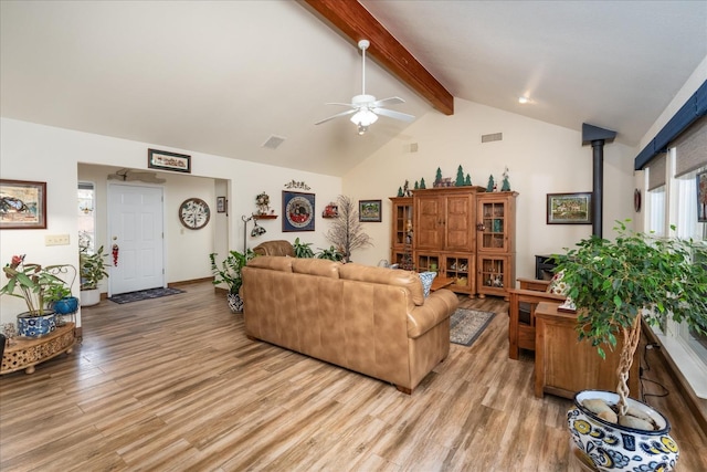 living room featuring a wood stove, lofted ceiling with beams, light hardwood / wood-style flooring, and ceiling fan