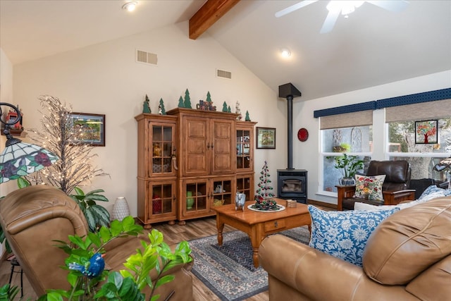 living room with hardwood / wood-style floors, lofted ceiling with beams, a wood stove, and ceiling fan