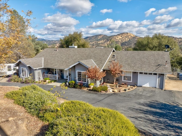 single story home with a mountain view, a porch, and a garage