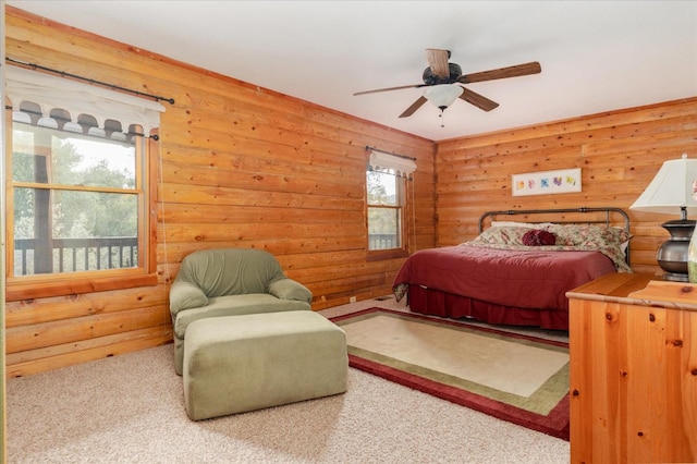 carpeted bedroom with ceiling fan, rustic walls, and multiple windows