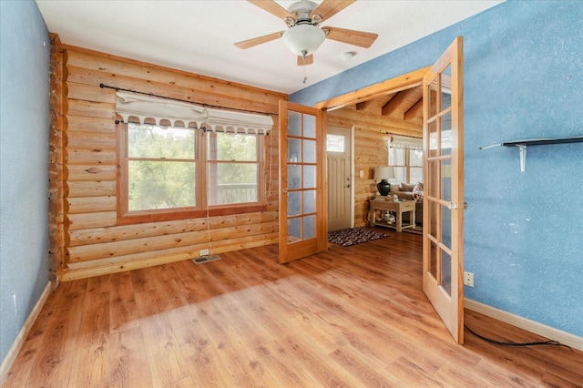 unfurnished room with hardwood / wood-style flooring, a healthy amount of sunlight, rustic walls, and french doors