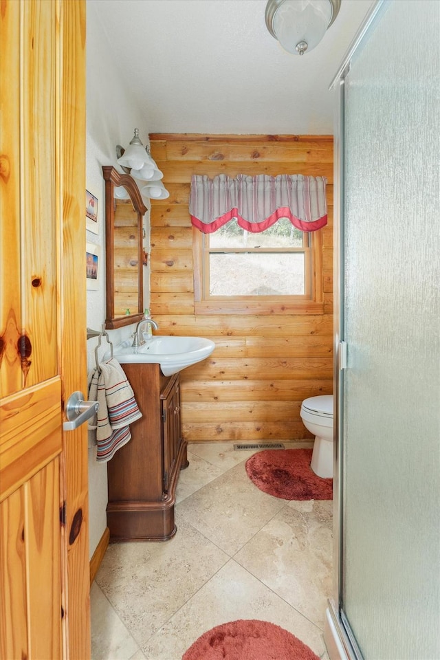 bathroom featuring tile patterned floors, rustic walls, walk in shower, vanity, and toilet