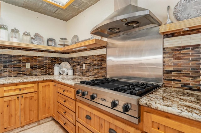 kitchen featuring stainless steel gas stovetop, decorative backsplash, island range hood, and light stone counters