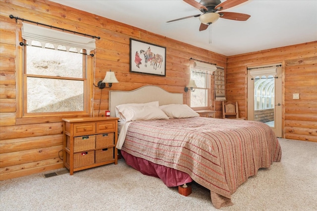 bedroom with ceiling fan, log walls, and light carpet