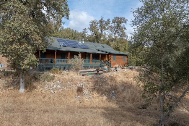 rear view of property with covered porch and solar panels