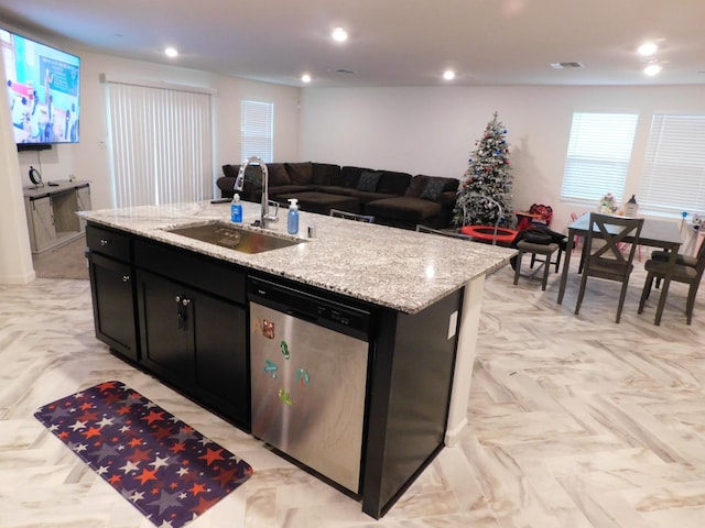 kitchen with light stone countertops, stainless steel dishwasher, a kitchen island with sink, and sink