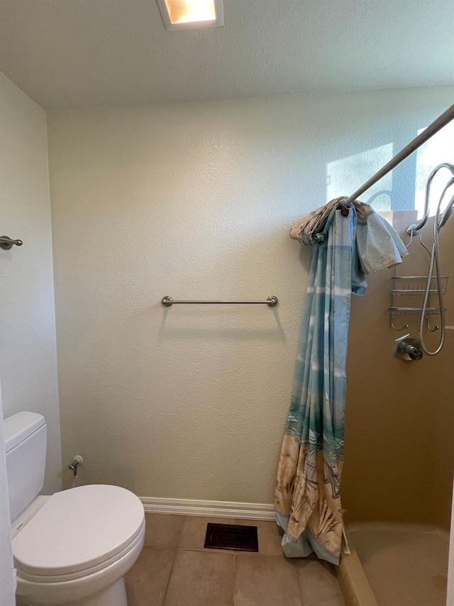 bathroom with toilet, a shower, and tile patterned flooring