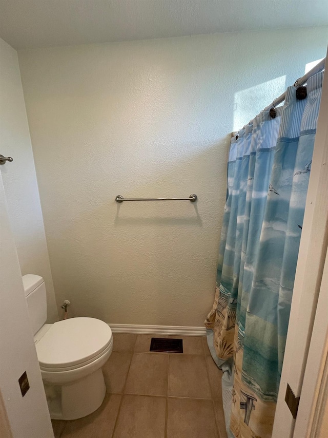 bathroom featuring toilet, a shower with shower curtain, and tile patterned flooring