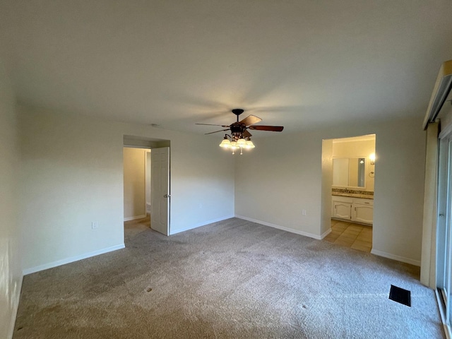 unfurnished bedroom featuring connected bathroom, light carpet, and ceiling fan