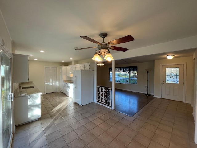 kitchen with white appliances, light tile patterned floors, white cabinets, ceiling fan, and sink