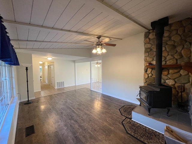 unfurnished living room with wooden ceiling, a wood stove, beamed ceiling, ceiling fan, and hardwood / wood-style floors