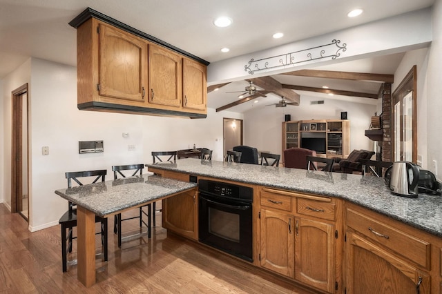 kitchen featuring kitchen peninsula, ceiling fan, wood-type flooring, vaulted ceiling with beams, and oven