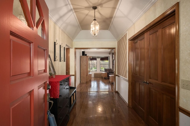 corridor with an inviting chandelier, ornamental molding, dark wood-type flooring, and vaulted ceiling