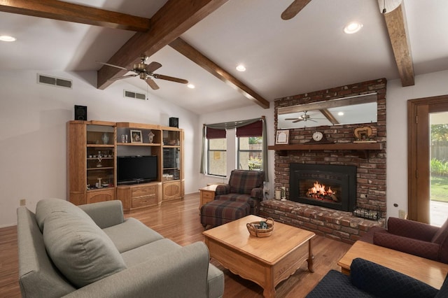 living room featuring a brick fireplace, lofted ceiling with beams, a wealth of natural light, and light hardwood / wood-style flooring