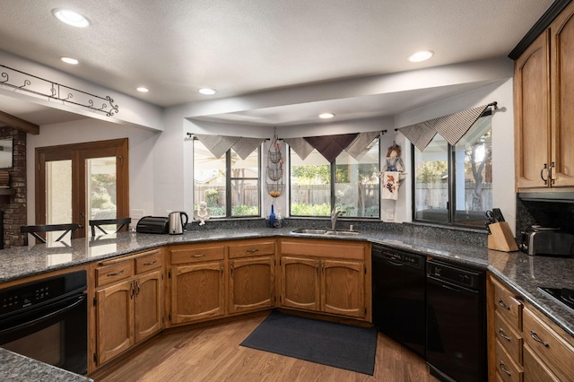 kitchen featuring black appliances, plenty of natural light, sink, and light hardwood / wood-style flooring