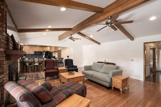 living room featuring light wood-type flooring, lofted ceiling with beams, and a fireplace