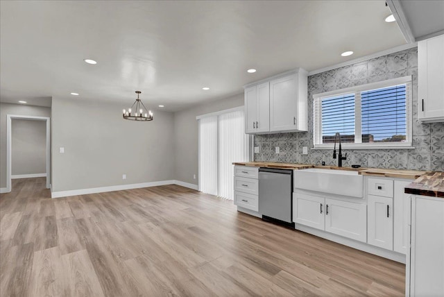 kitchen featuring butcher block counters, dishwasher, white cabinets, and hanging light fixtures