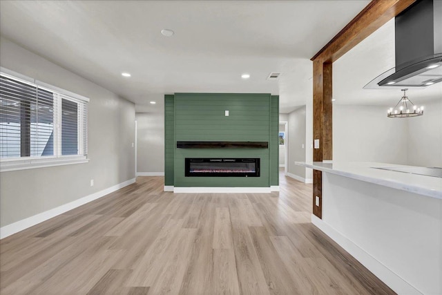 unfurnished living room featuring light wood-type flooring, a fireplace, and an inviting chandelier