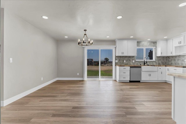 kitchen featuring white cabinetry, hanging light fixtures, and stainless steel dishwasher