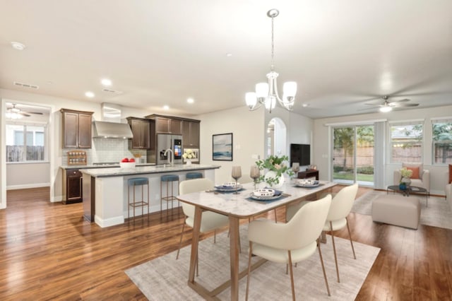 dining area featuring ceiling fan with notable chandelier, dark hardwood / wood-style floors, and sink