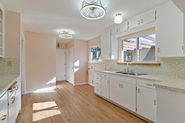 kitchen featuring decorative backsplash, sink, white cabinets, and light hardwood / wood-style floors