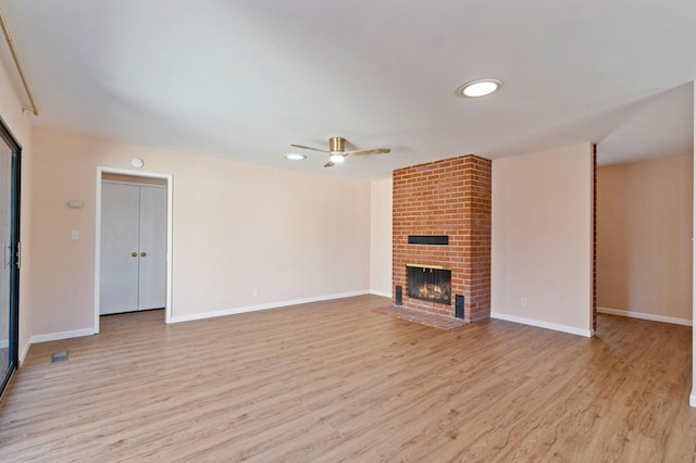 unfurnished living room with ceiling fan, a fireplace, and light hardwood / wood-style flooring